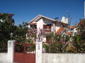 A two-story house with a balcony, surrounded by a fence and various plants. - Discover the perfect getaway in the heart of Vouzela and feel the rhythm of nature! (Vouzela)