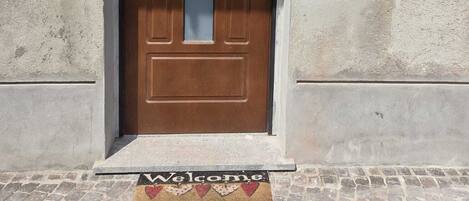 A brown door with a glass panel, a mail slot, and a doormat with 'Welcome' written on it.