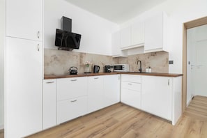 Eine moderne Küche mit weißen Schränken, einer Holz Arbeitsplatte und einer Mikrowelle.