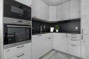 A modern kitchen with a built-in oven, microwave, and a coffee maker on the counter. - Spacious Apartment with Balcony and Desk | Bathtub (Kraków)