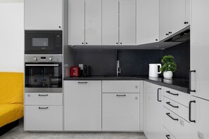 Eine moderne Küche mit grauen Schränken, einer Mikrowelle, einem Backofen und einer Kaffeemaschine.