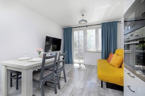 A modern kitchen with a built-in oven and a dining area with a table and chairs. - Spacious Apartment with Balcony and Desk | Bathtub (Kraków)