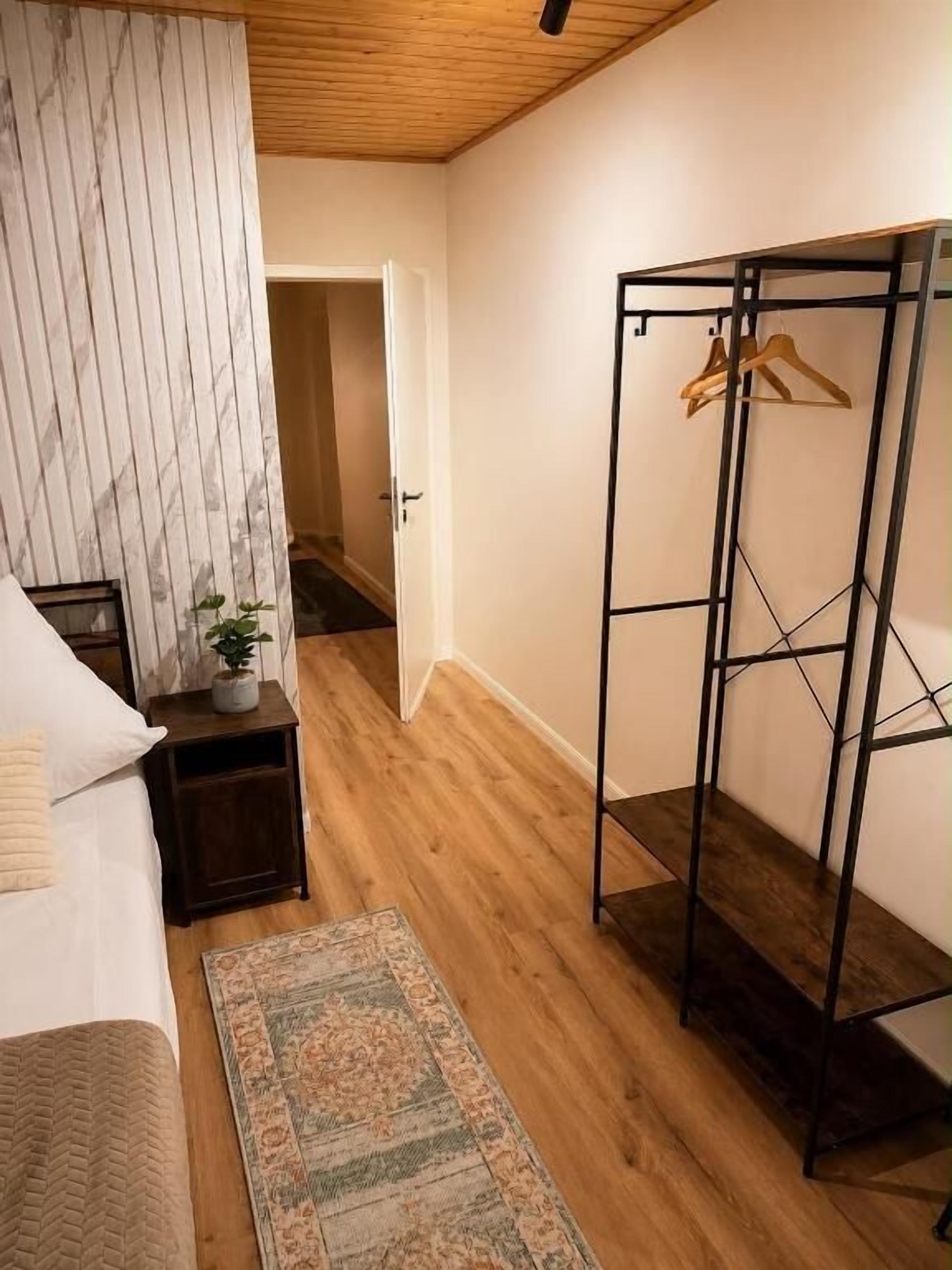 Een slaapkamer met een bed, nachtkastje en een houten vloer.