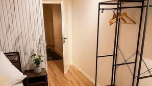 Un dormitorio con cama, mesita de noche y suelo de madera.