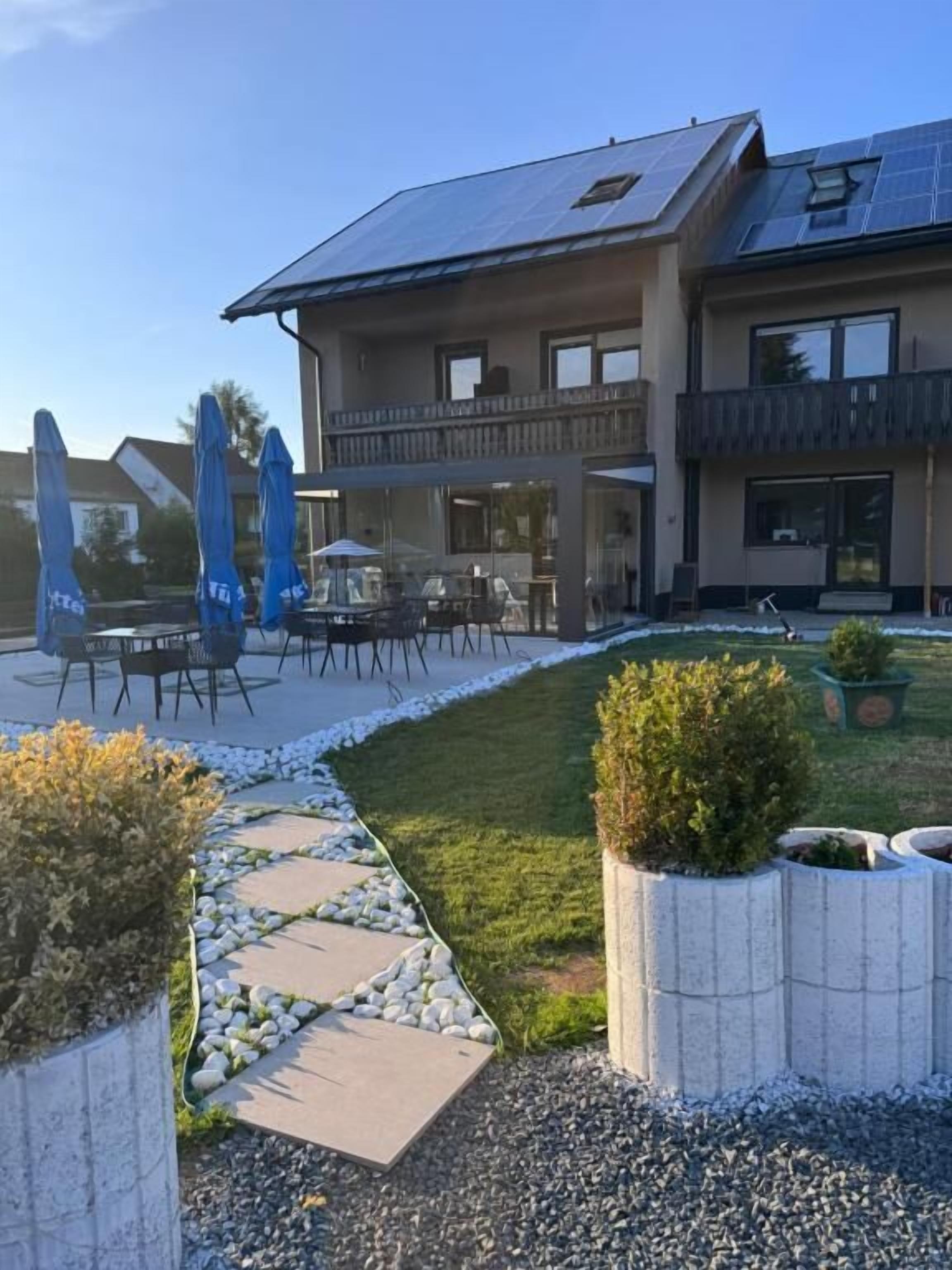 A modern building with a balcony, outdoor seating, and solar panels.