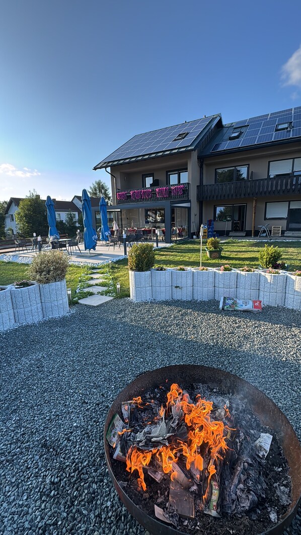A building with a fire pit in the foreground, surrounded by gravel.