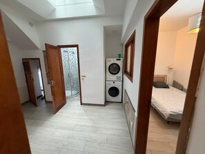A compact living space with a skylight, a washing machine, and a bed. - Las Palmas Castillo Albrit Community Center (Las Palmas de Gran Canaria)