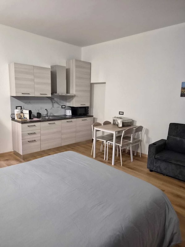 A modern, minimalist bedroom with a large bed, a small desk, and a chair.