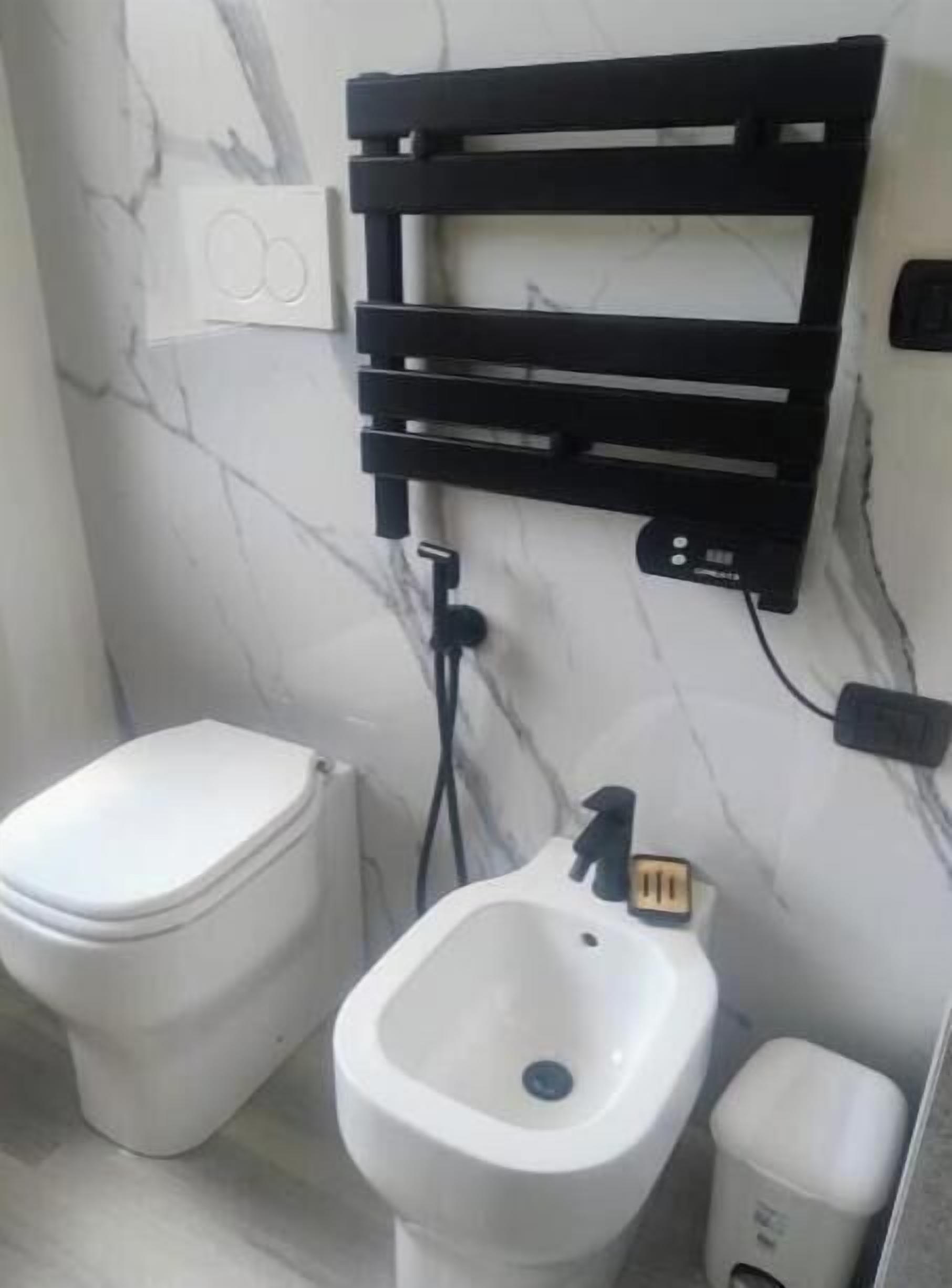 Una presa elettrica nera con una spina inserita, fissata a una parete bianca con crepe visibili.