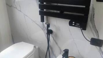 Una presa elettrica nera con una spina inserita, fissata a una parete bianca con crepe visibili.