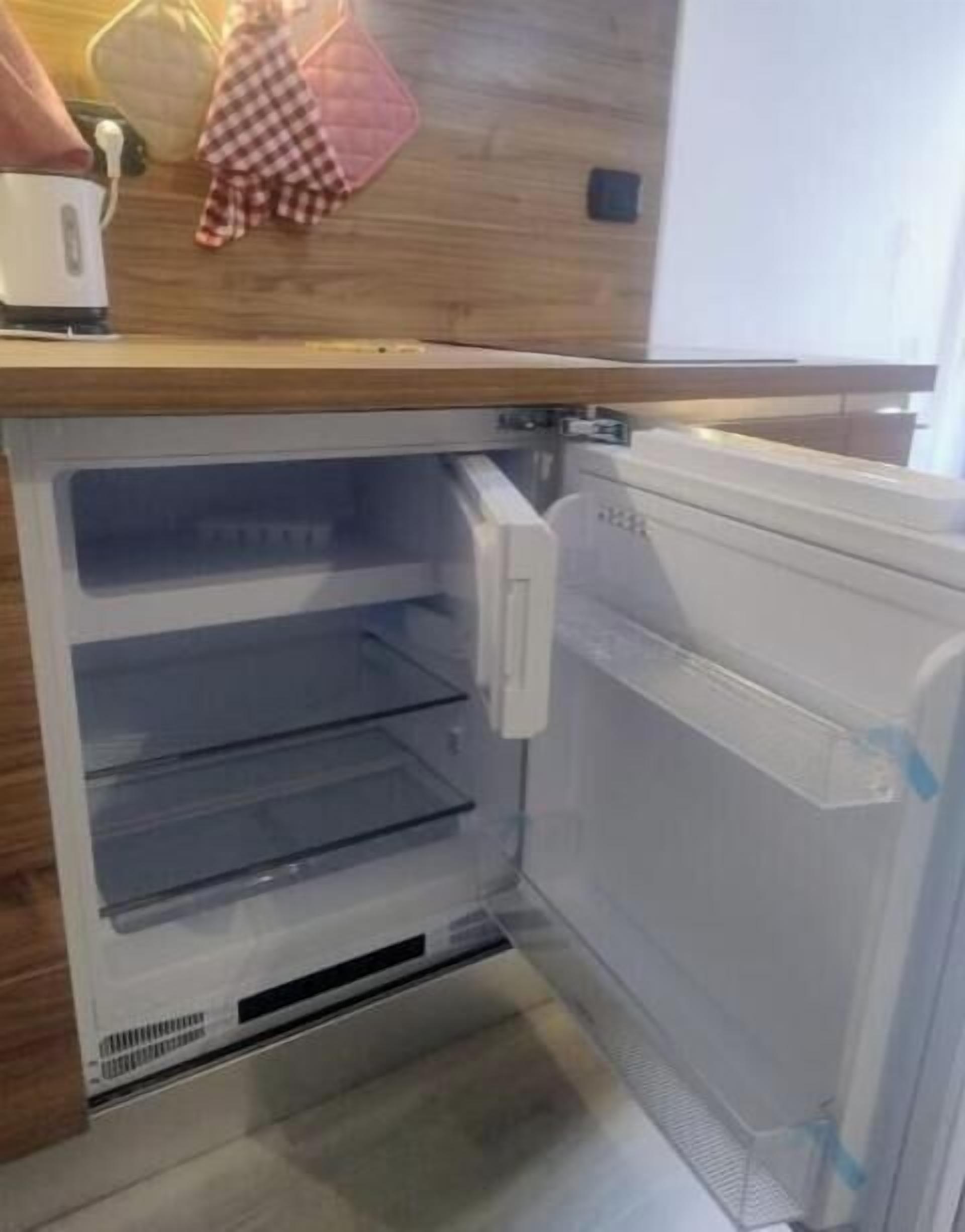 Een keuken met een inbouwkoelkast, een magnetron en een houten aanrecht.