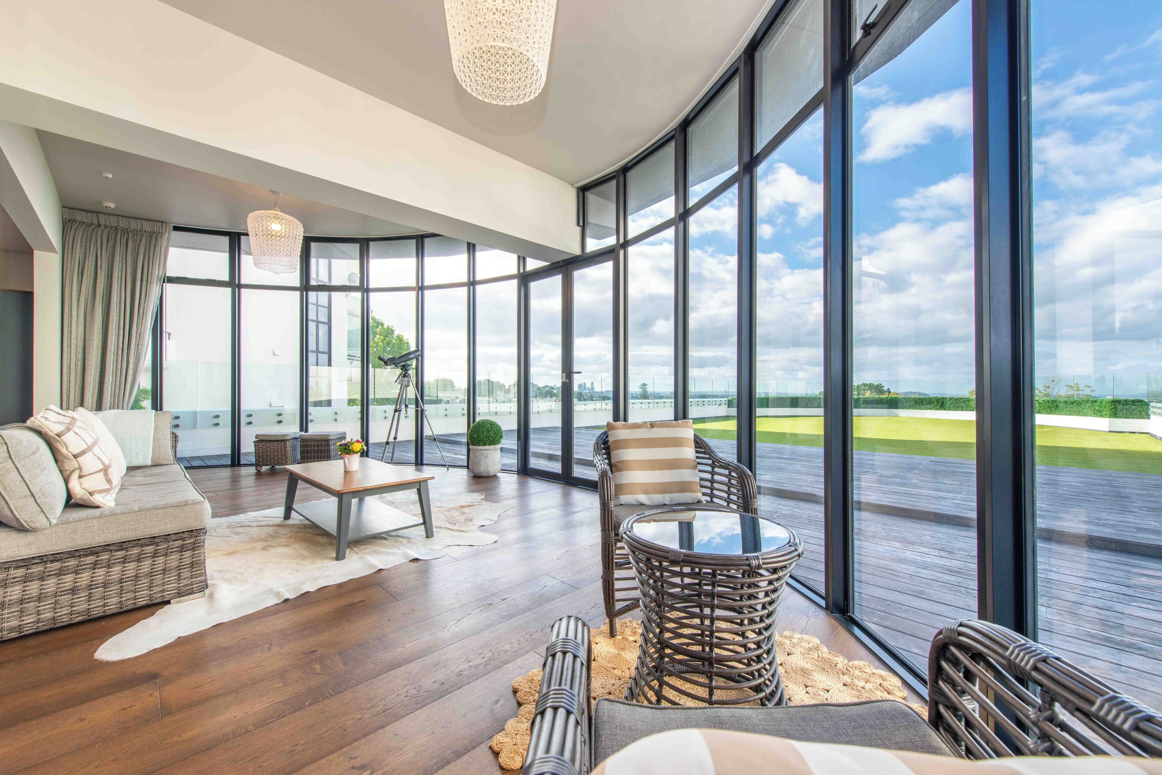 A spacious living area with a large window, a sofa, a coffee table, and a wicker chair.