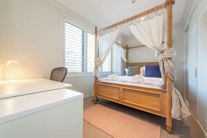 A bedroom with a four-poster bed, a bedside table, a chair, and a window with blinds. - Luxury 3BR Apartment with Stunning Views | Remuera (Auckland)