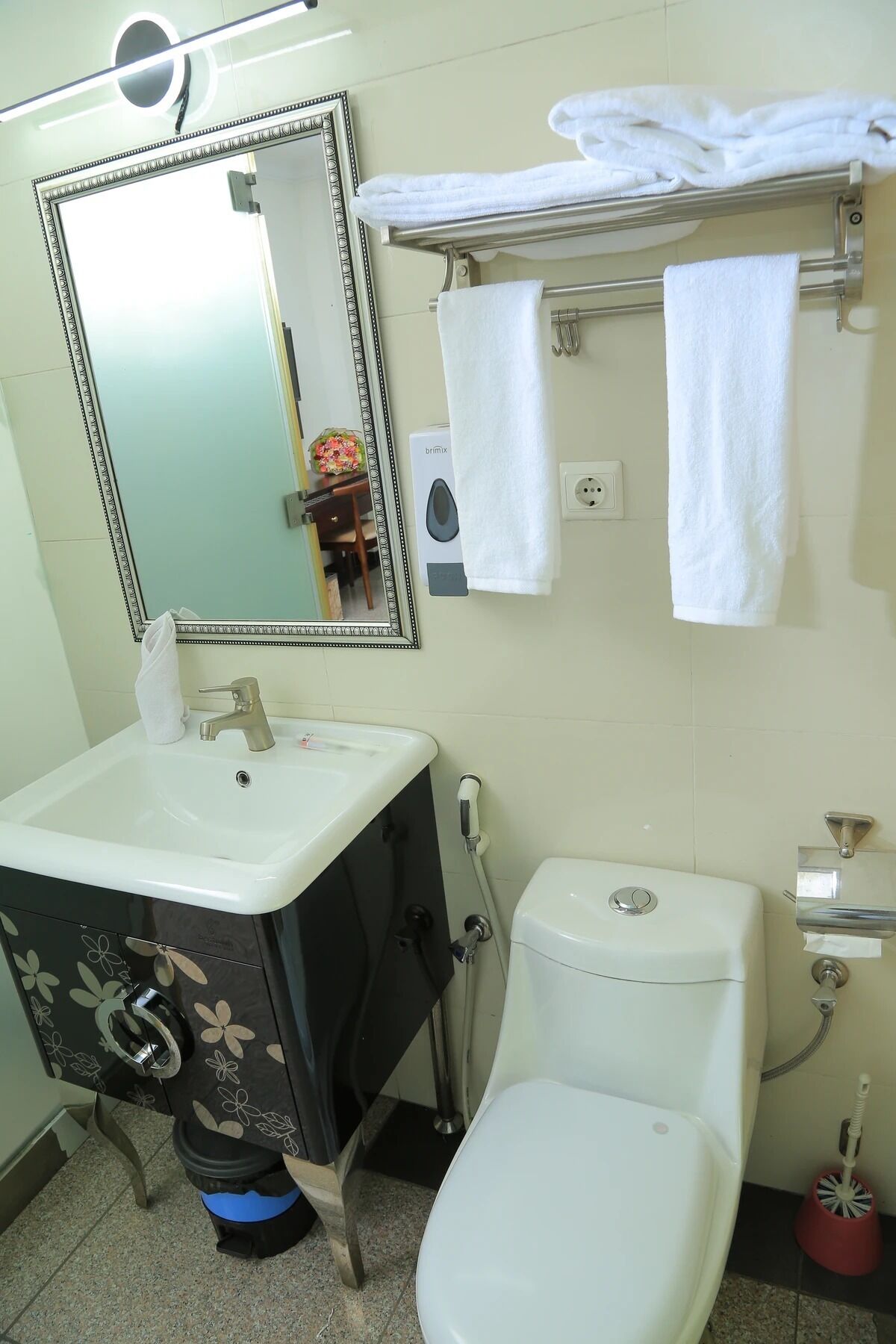 A bathroom with a sink, mirror, toilet, and towel rack.