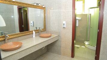A bathroom with two sinks, a large mirror, and a shower area.