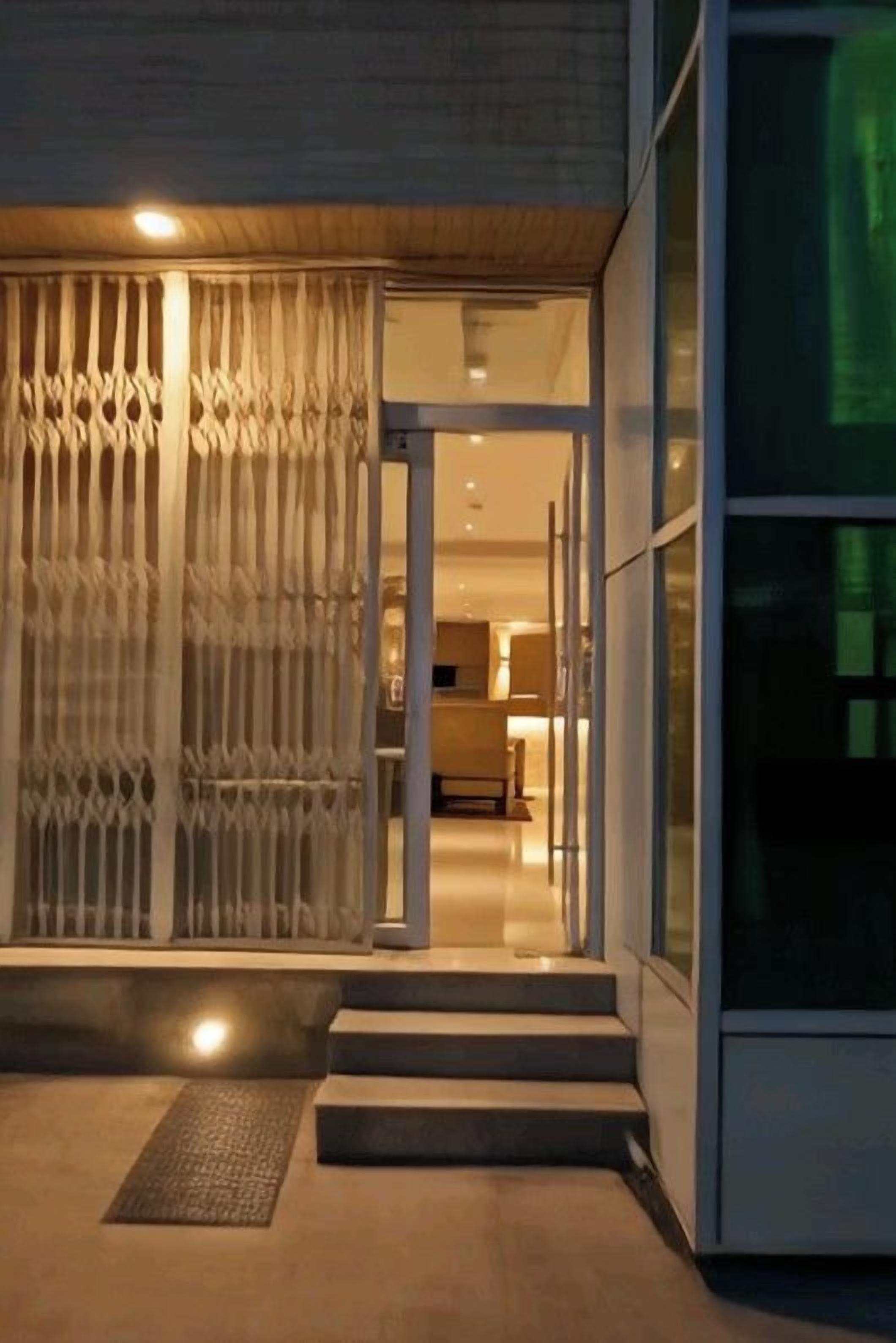 A modern building entrance with a glass door, steps, and a metal gate.