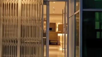 A modern building entrance with a glass door, steps, and a metal gate.