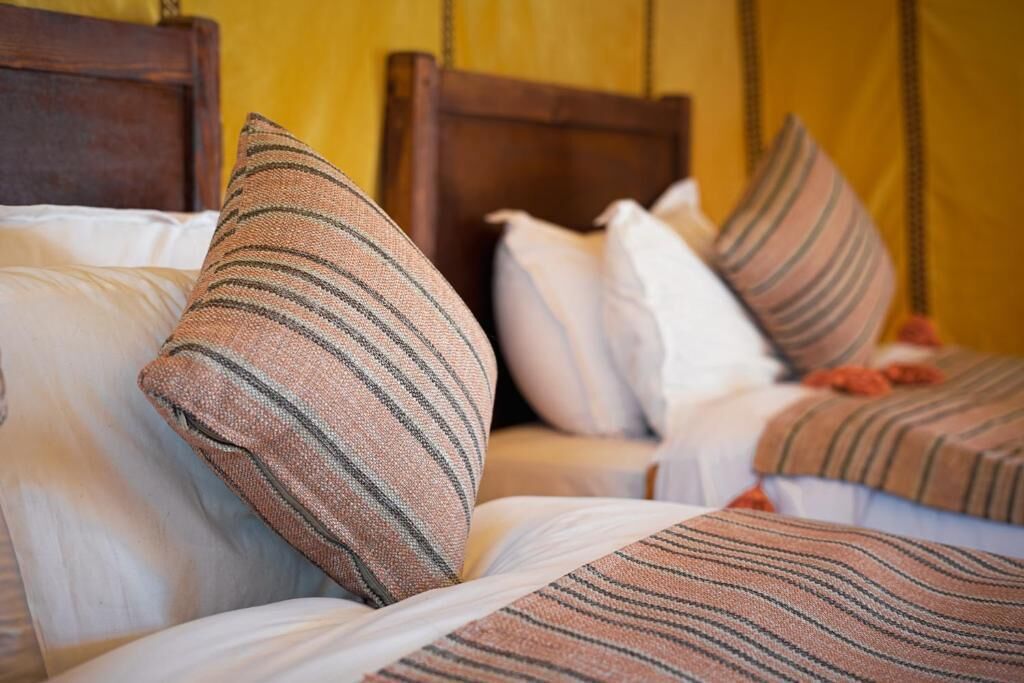 Een bed met gestreepte kussens en een houten hoofdbord.
