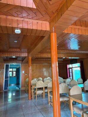 Una habitación con paneles de madera, piso de baldosas y varias mesas con sillas.