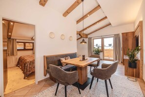 A modern interior with a dining area, a sofa, and a view of the outside. - Mocking Ferienappartements (Kitzbühel)
