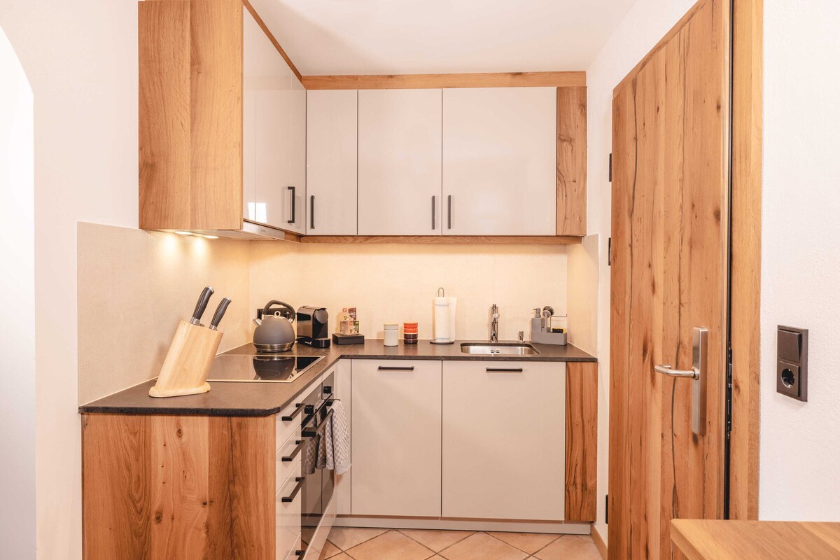 A compact kitchen with wooden cabinets, a black countertop, and basic appliances.