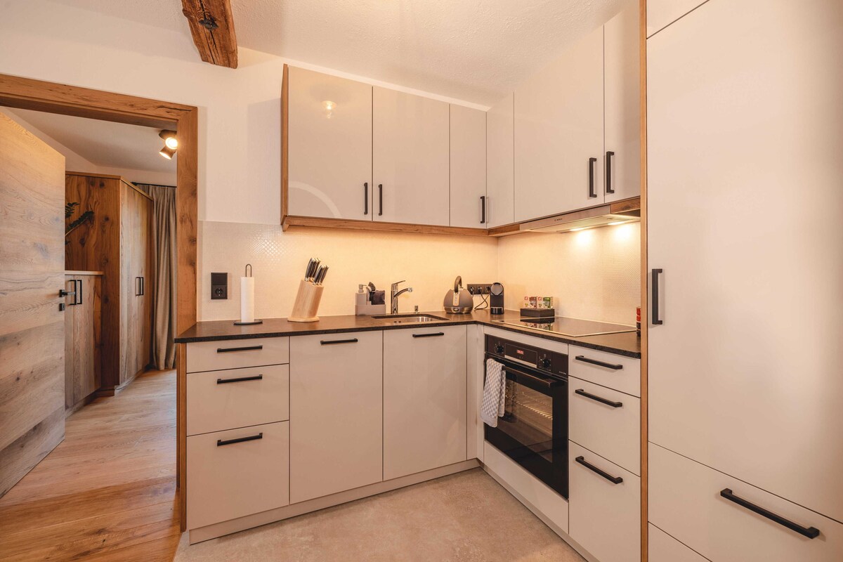 A modern kitchen with wooden cabinets, a built-in oven, and a countertop with various appliances.