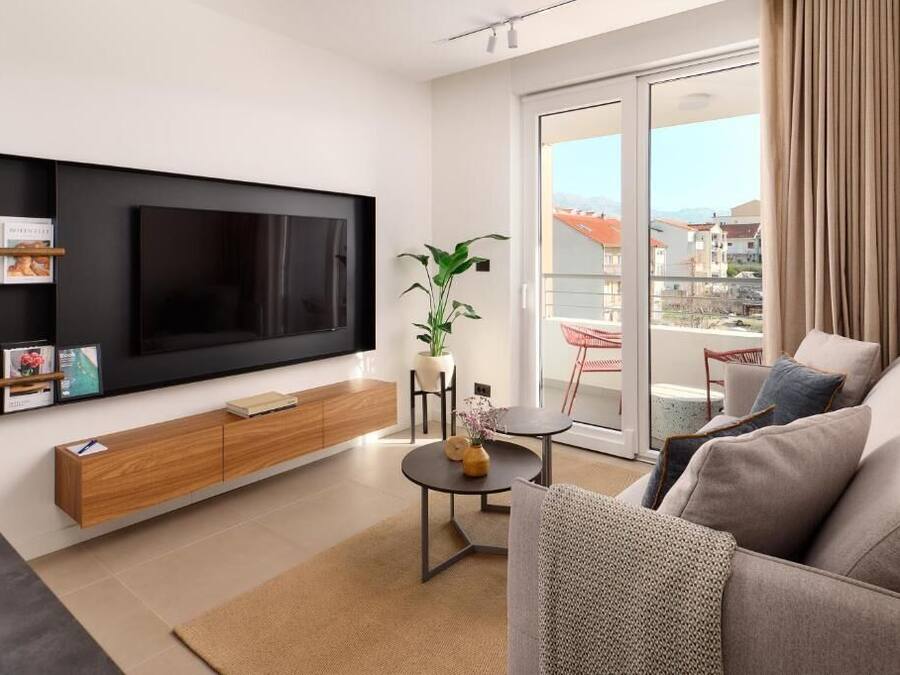 Una sala de estar moderna con un televisor de pantalla plana, un mueble de madera y una planta.