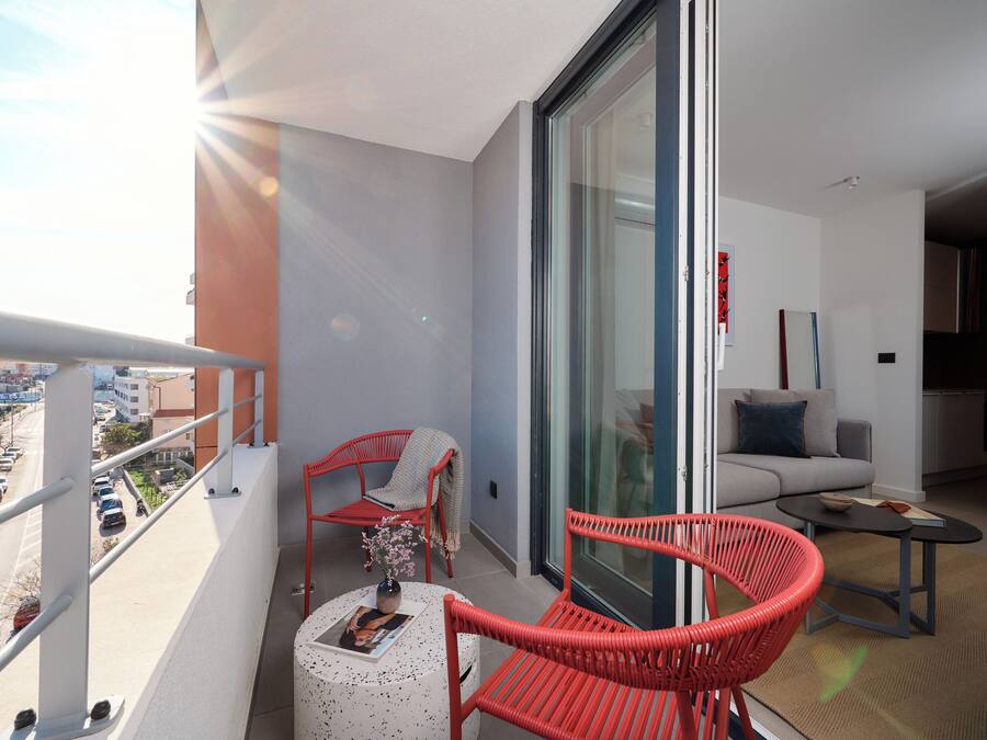 A balcony with a table, chairs, and a view of the city.
