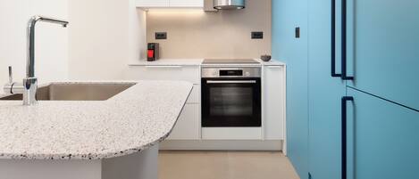 A modern kitchen with a granite countertop, stainless steel appliances, and blue cabinetry.