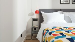 Una habitación de hotel con una cama, una mesita de noche, una lámpara y una lámpara de pared.