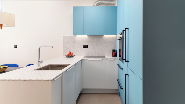Una cocina moderna con encimera de granito, pileta de acero inoxidable y muebles azulados.