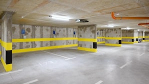 Un estacionamiento de varios niveles con paredes de concreto, líneas de seguridad amarillas y espacios de estacionamiento numerados.
