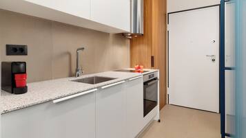 Una cocina moderna con armarios blancos, un lavamanos de acero inoxidable, un horno empotrado y una pared de acento de madera.