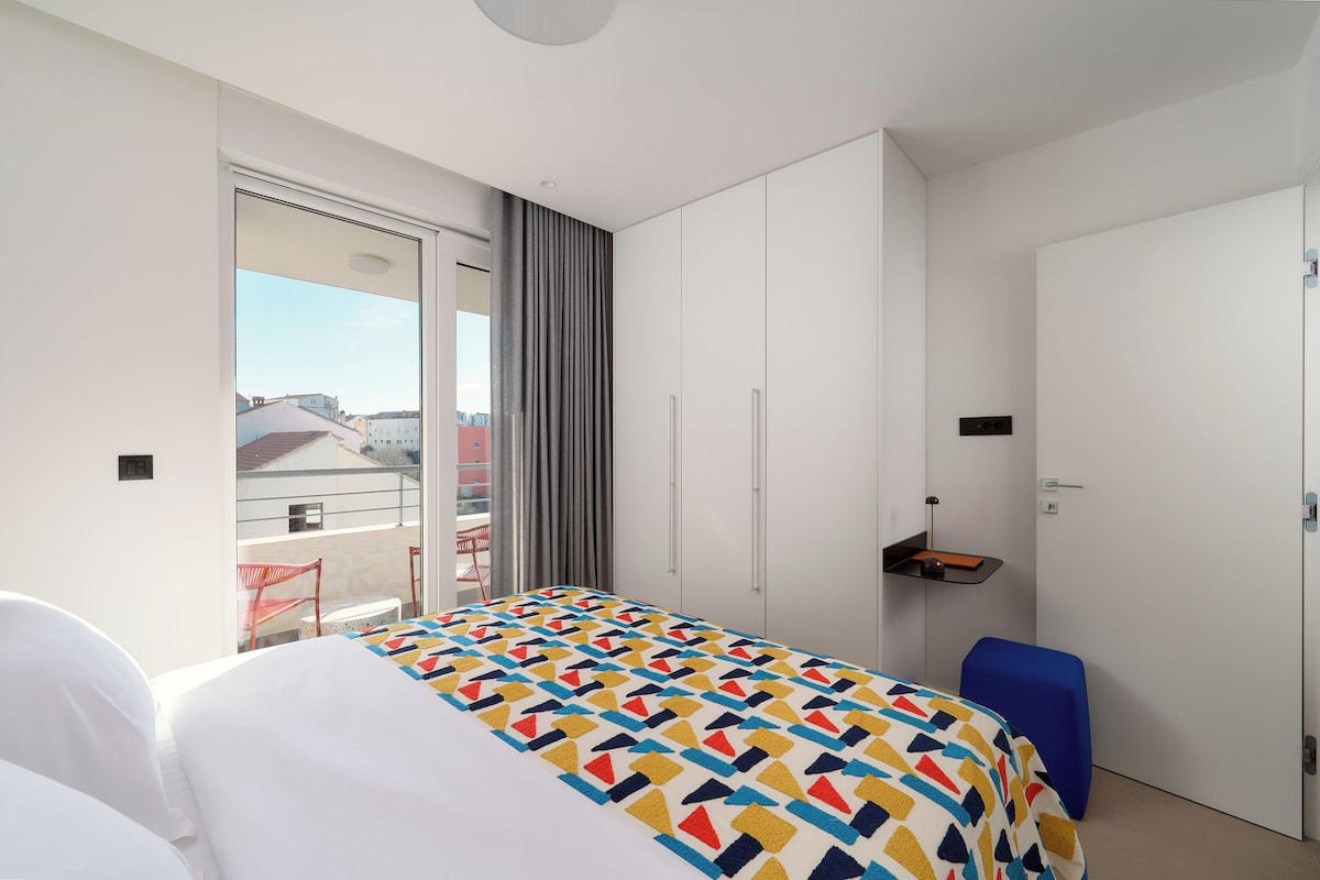 Una habitación de hotel con cama, ventana con vistas, armario y una pequeña mesa.