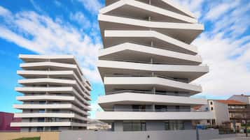 Un edificio moderno de varios pisos con un diseño arquitectónico único en zigzag, con balcones y ventanas grandes.