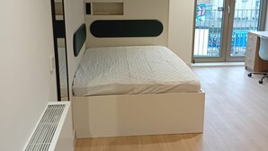 A modern bedroom with a built-in bed, a large mirror, and a sliding glass door leading to a balcony. - Student Only The Keel Houses (Edinburgh)