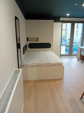A modern bedroom with a built-in bed, a large mirror, and a sliding glass door leading to a balcony. - Student Only The Keel Houses (Edinburgh)