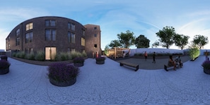 A modern building with a curved facade, outdoor seating area, and landscaped garden. - Student Only The Keel Houses (Edinburgh)