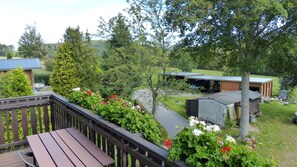 A wooden deck with a bench, surrounded by lush greenery and flowering plants. - Apartment 'FeWo Pyramide' with Shared Garden and Wi-Fi (Marienberg)