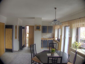 A dining area with a table, chairs, and a potted plant. There is a kitchen area with cabinets and a sink. - Apartment 'FeWo Pyramide' with Shared Garden and Wi-Fi (Marienberg)