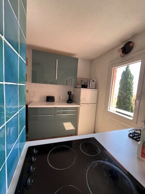A kitchen with a stove, microwave, and cabinets. - Ocean view & terrace – 10 min from Saint-Tropez – Pool, tennis court, private parking (La Croix-Valmer)