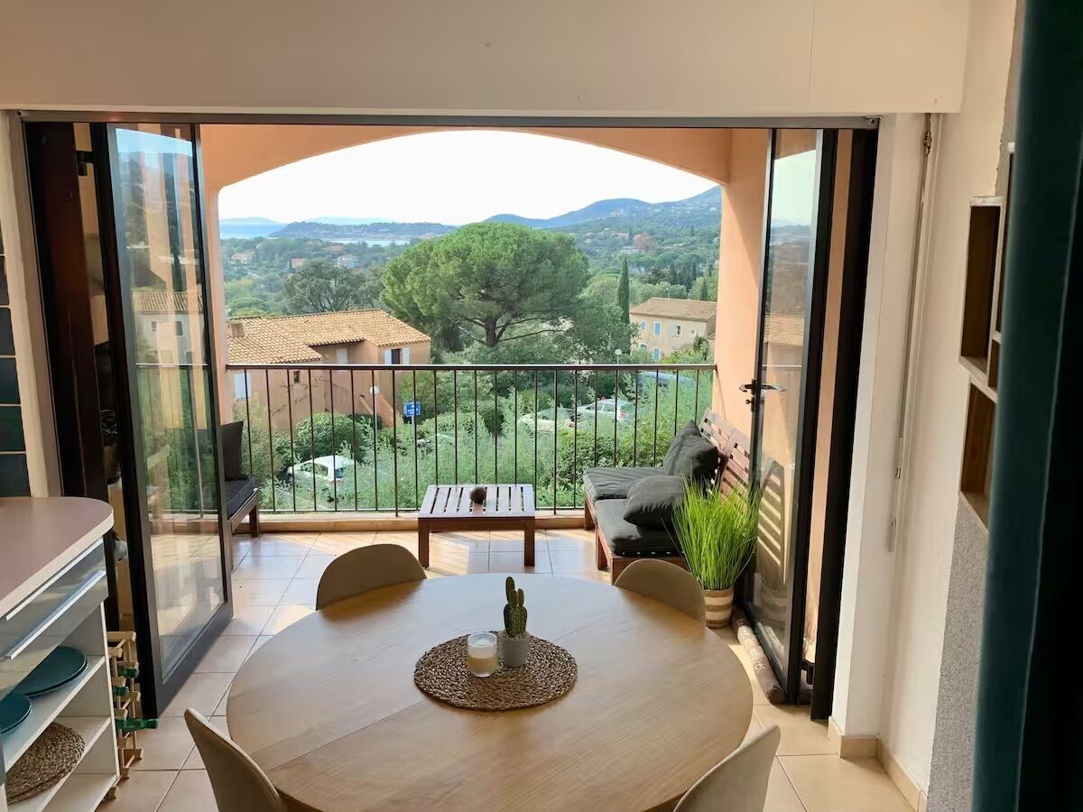 Ein Balkon mit Tisch, Stühlen und einer Bank, mit Blick auf eine ländliche Landschaft.