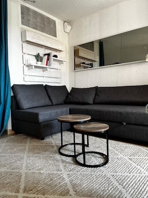 A modern living room with a sectional sofa, two round coffee tables, and a built-in bookshelf. - Ocean view & terrace – 10 min from Saint-Tropez – Pool, tennis court, private parking (La Croix-Valmer)