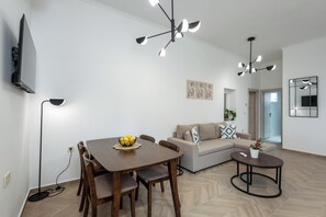 A modern living room with a dining table, sofa, and a small coffee table. - Marilianas Apartment (Platanias)