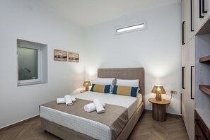 Een moderne slaapkamer met een groot bed, twee nachtkastjes met lampen, een raam en kunst aan de muur.