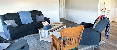 Un salon comprenant un canapé, un fauteuil à bascule, une table basse et un tapis.