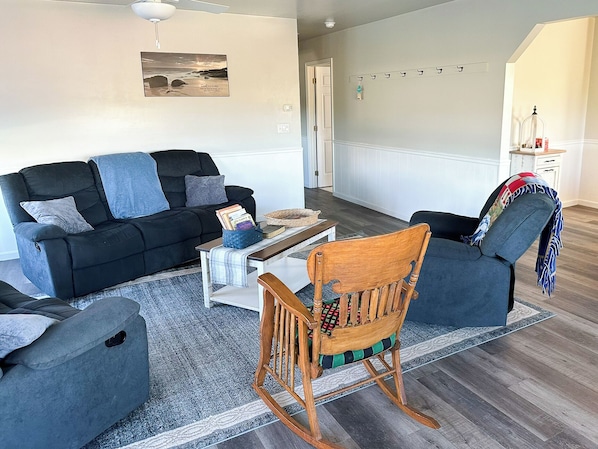 A living room with a sofa, a rocking chair, a coffee table, and a rug.