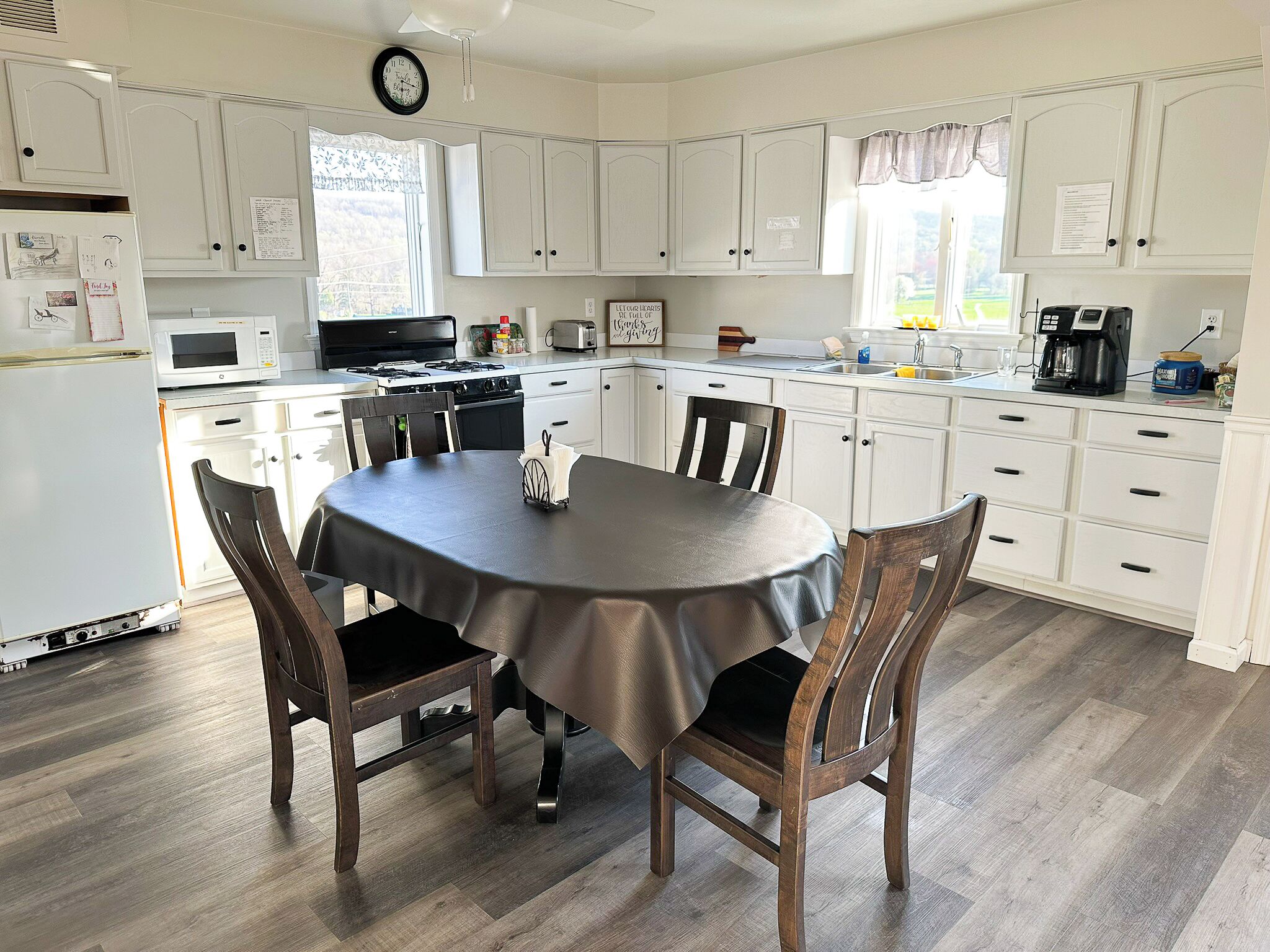 Une cuisine avec des meubles blancs, une cuisinière, un évier et une table à manger avec des chaises.