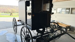 A covered carriage with large wheels parked inside a garage.