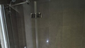 Et badeværelse med et glasafskærmet brusebad, en hvid vask og et badekar.